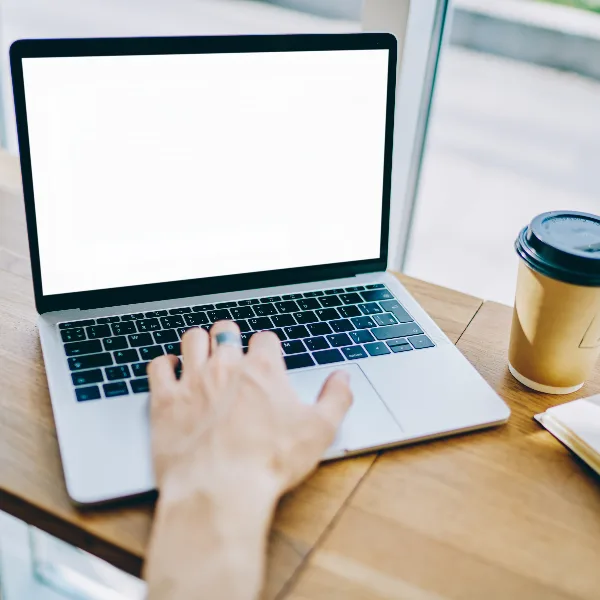 ręka mężczyzny na klawiaturze laptopa z białym ekranem, obrazek jest koncepcją ilustrującą temat "prywatne przeglądarki"