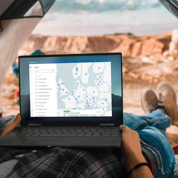 Mężczyzna na wycieczce, siedzący w namiocie, używa NordVPN na laptopie